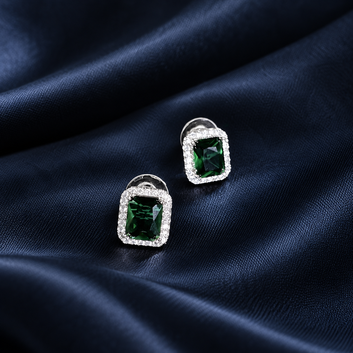Close-up of emerald-green halo stud earrings