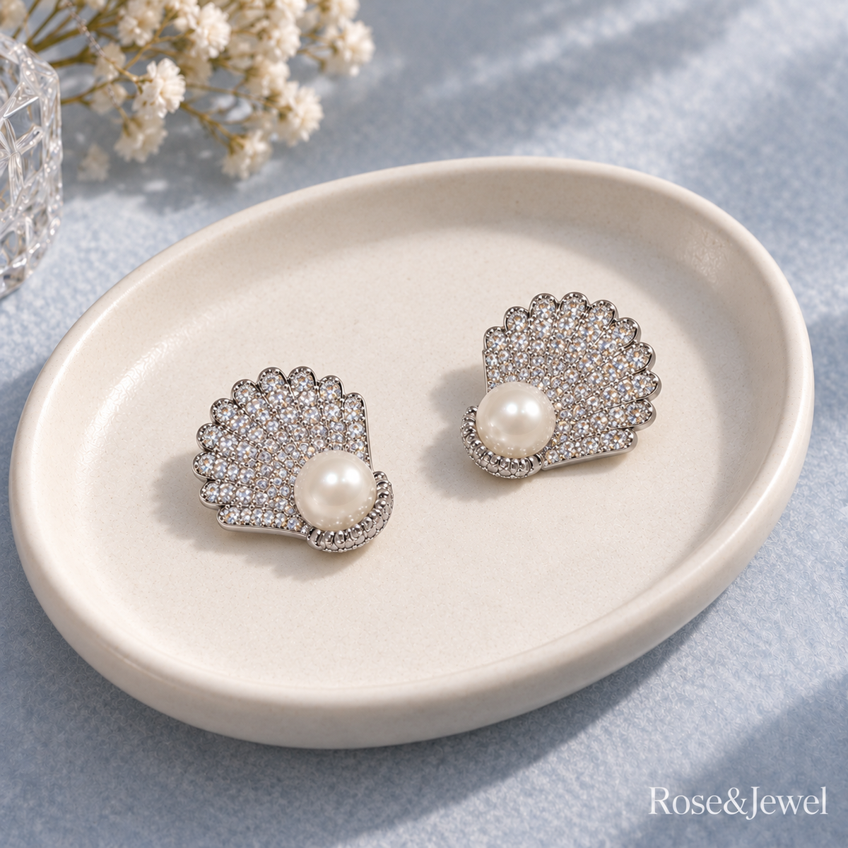Scallop shell stud earrings resting on an ivory tray